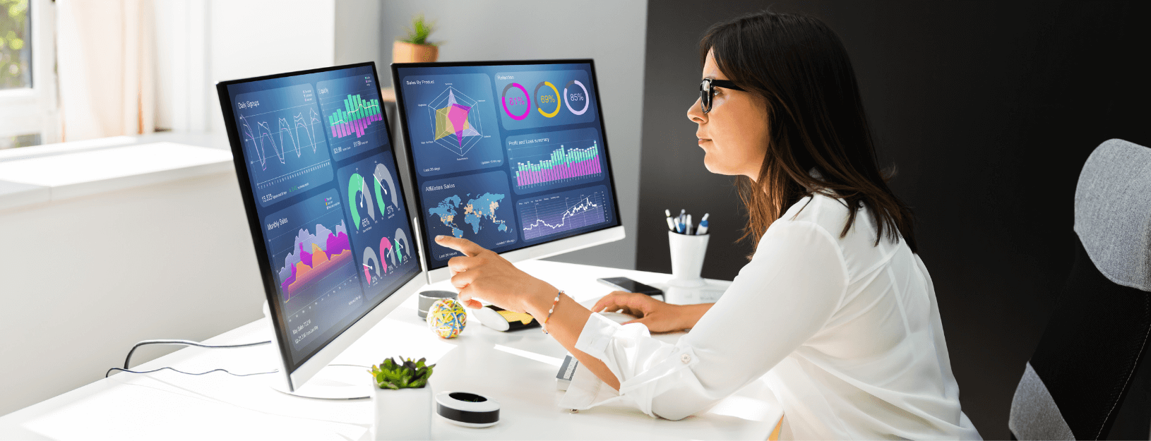 A woman reviewing data visualization on two computer screens