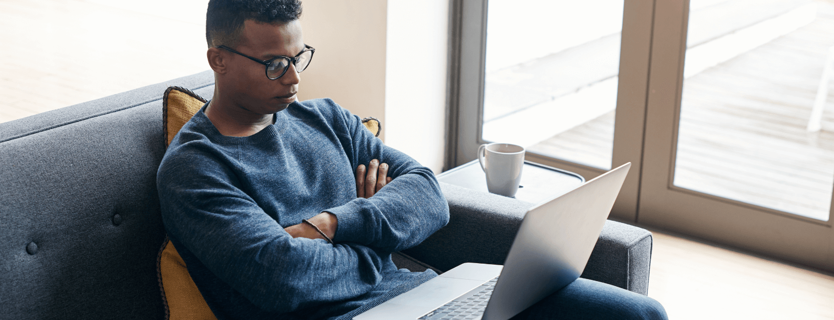 A man is frustrated while waiting for something to load on his laptop.