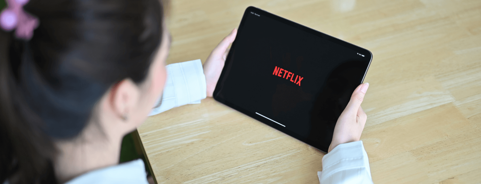 A woman looks at Netflix on her tablet device. 