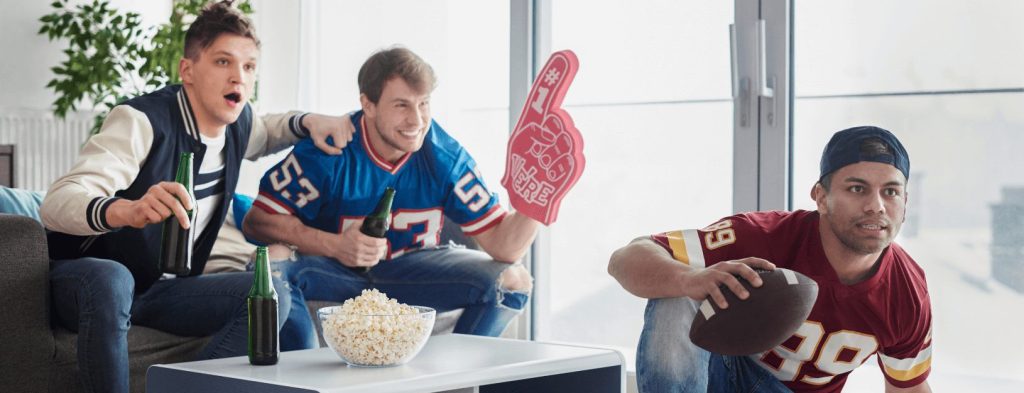 Three friends are watching the football game at home.