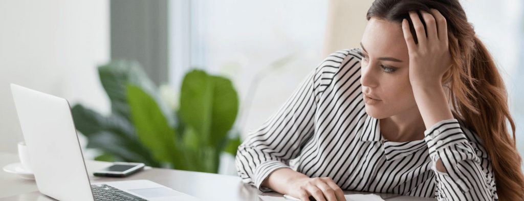 A woman is bored while looking at her laptop