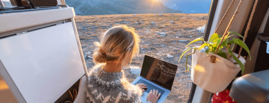 A woman is accessing the internet on her laptop while parked in a rural area.